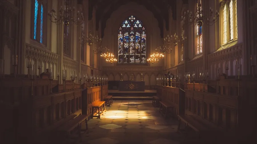 Interior de una iglesia con vitrales, bancas de madera y altar