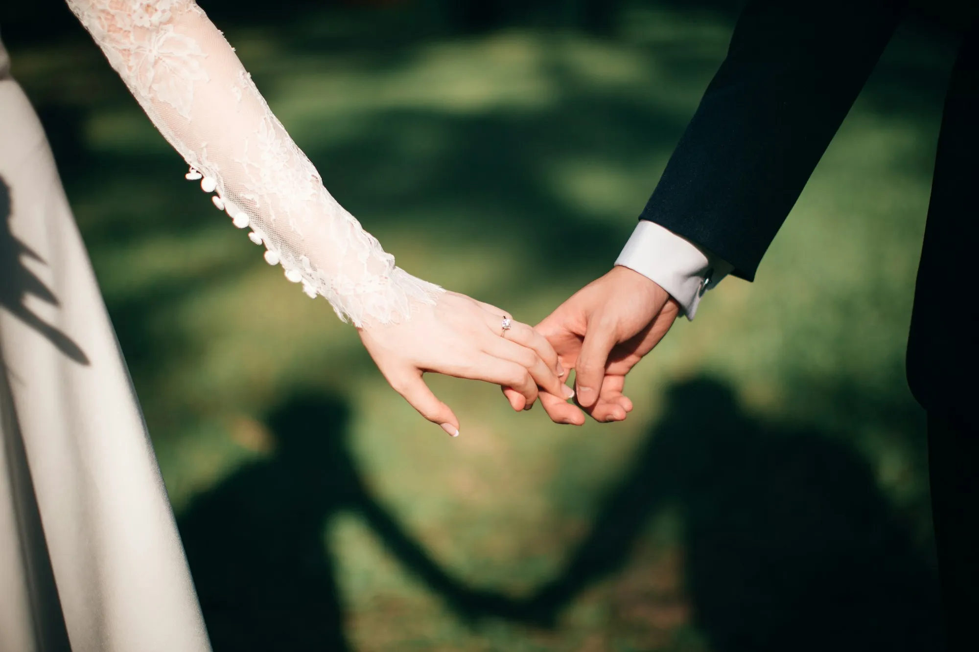 Las manos de los novios entrelazadas sobre el jardín