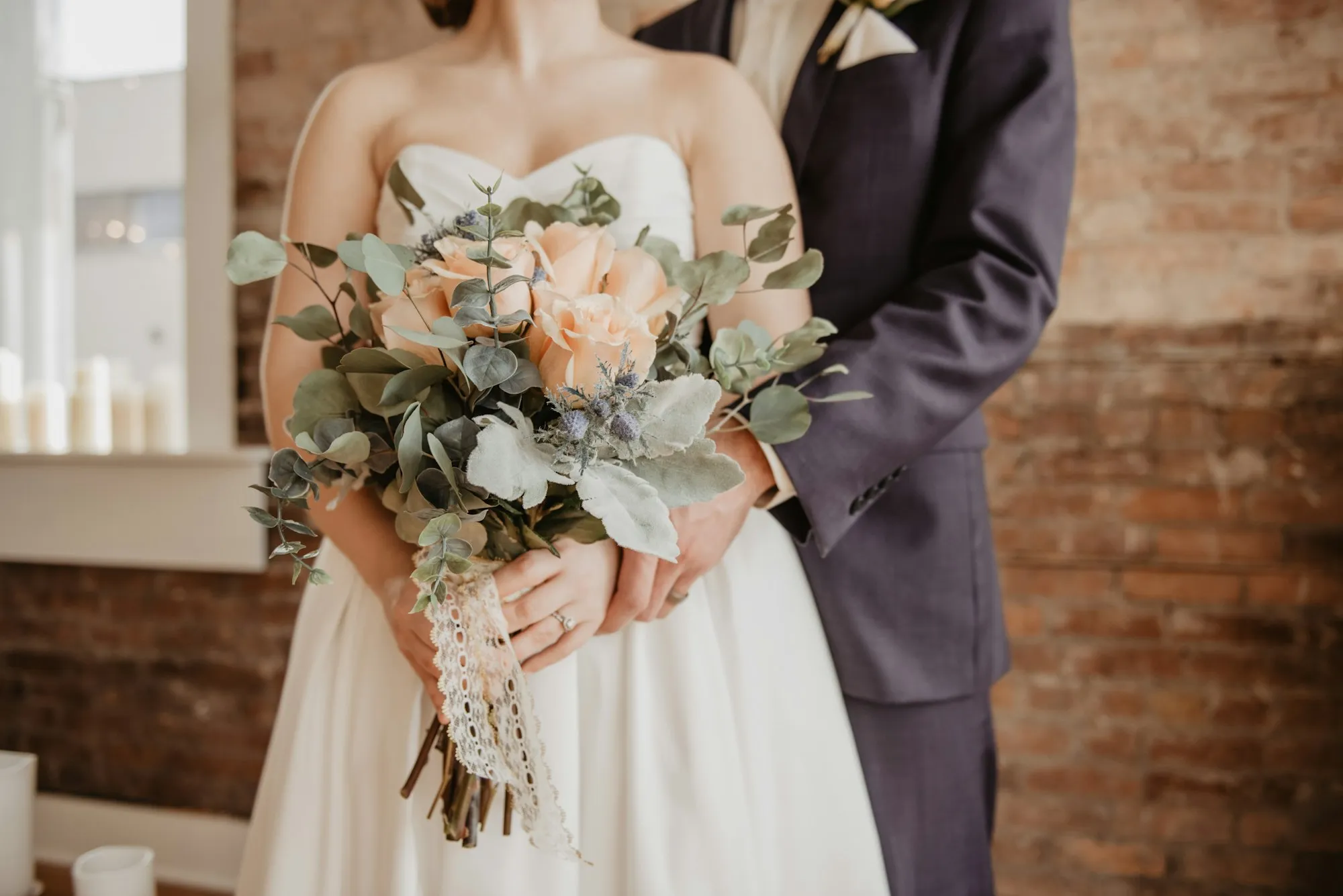 Los novios de pie, ella sosteniendo el ramo entre los dos
