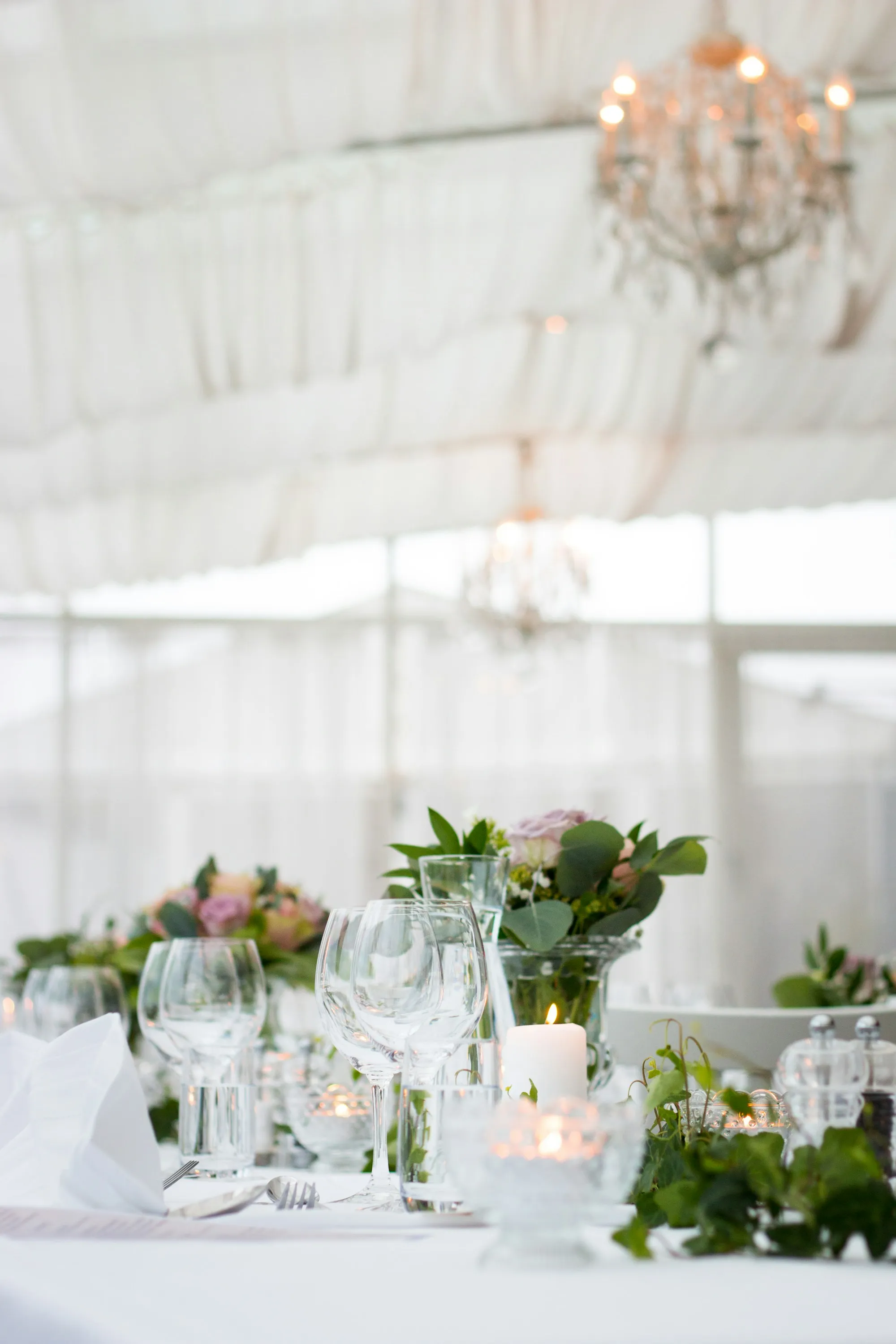 Mesa de banquete puesta, con copas, velas y follaje
