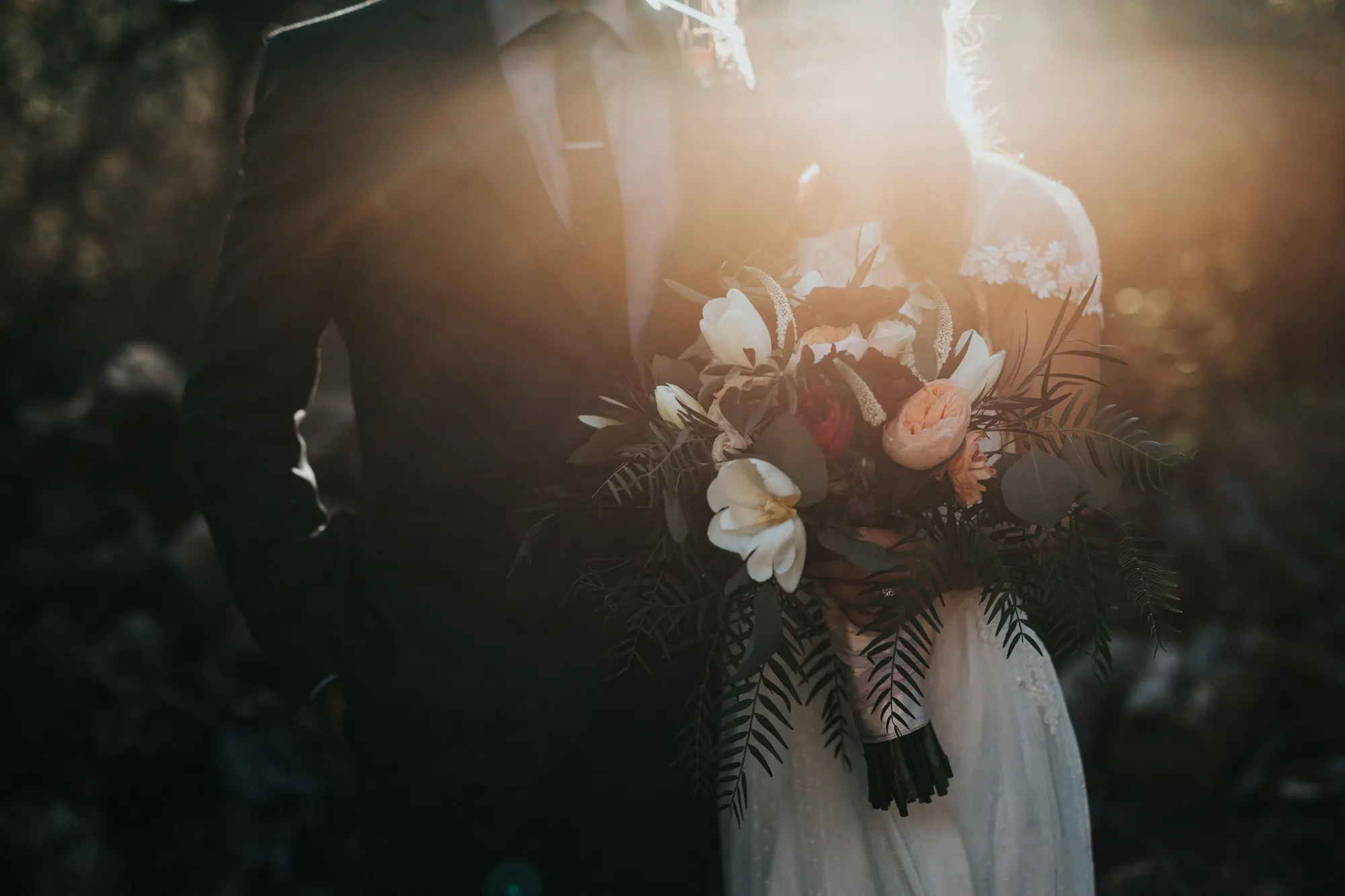Los novios a contraluz, ella con el ramo entre los dos