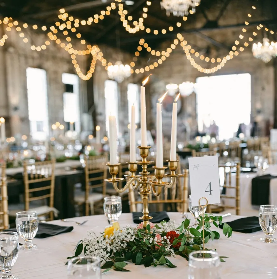 Salón de banquete con mesas puestas, velas y guirnaldas de luces